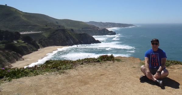 Alex sitting on a cliff with the Pacific Ocean in the background.